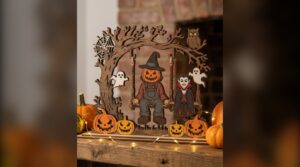 Layered laser cut swing scene with a scarecrow and a vampire among pumpkins and fairy lights